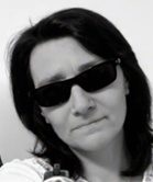 Frau mit dunklen Sonnenbrillen und ernstem Gesichtsausdruck.